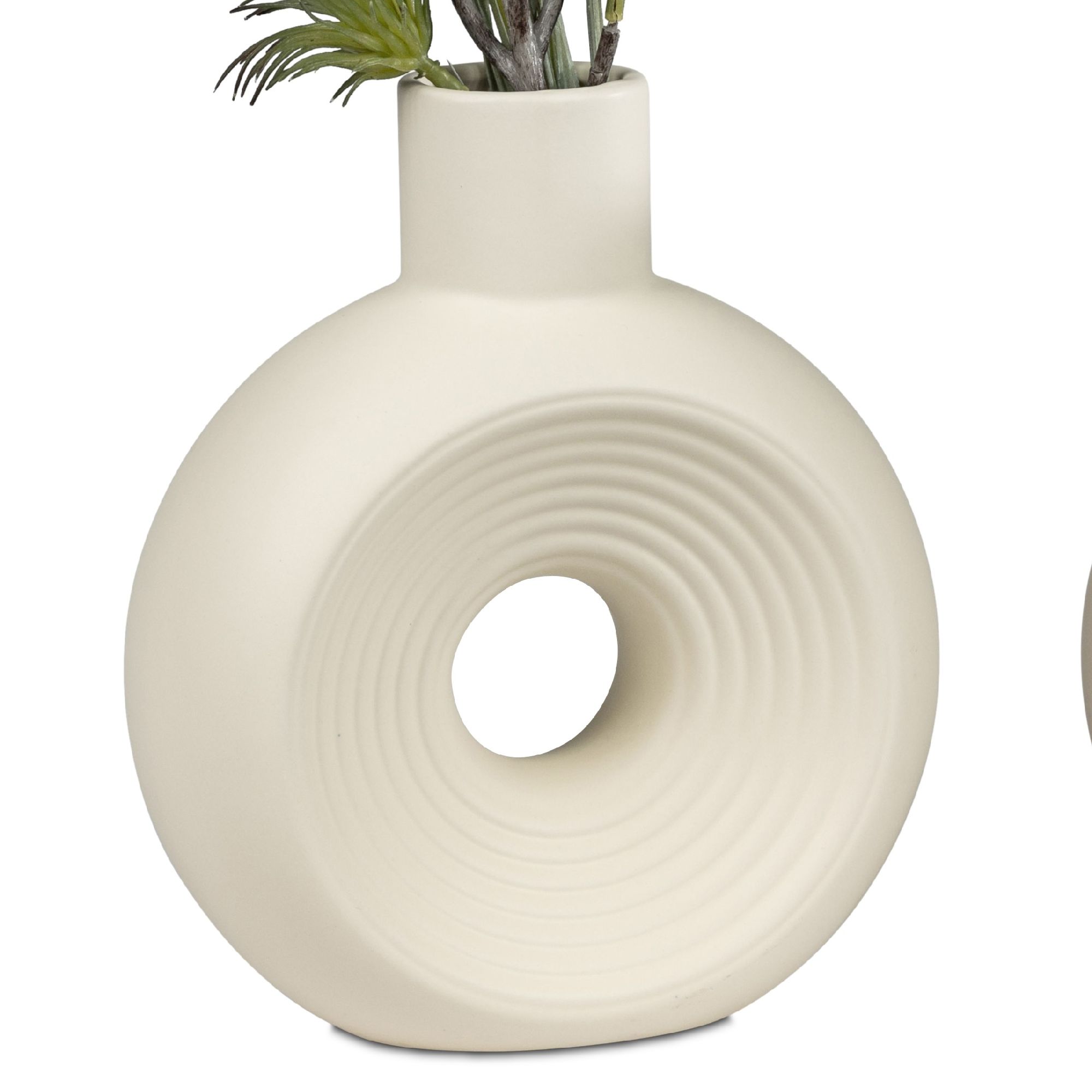 Eine runde, cremefarbene Vase mit einem zentralen Loch und wellenförmigen Mustern, gefüllt mit Pflanzen.