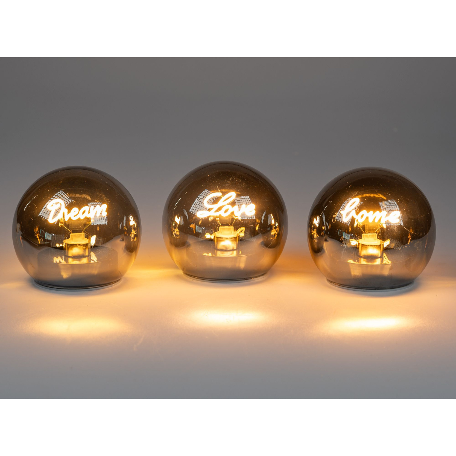 Drei runde Lampen mit spiegelndem Finish, beschriftet mit ""Dream"", ""Love"" und ""Home"", leuchten