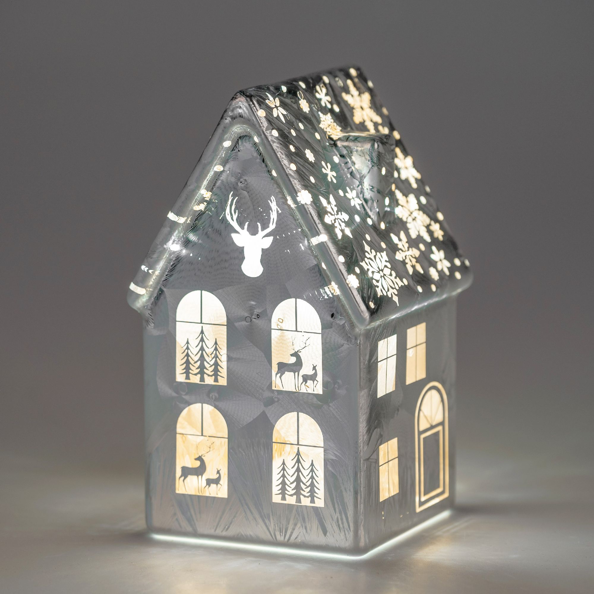 Ein dekoratives Haus aus Glas mit einem schneebedeckten Dach, Fenstern und winterlichen Motiven wie