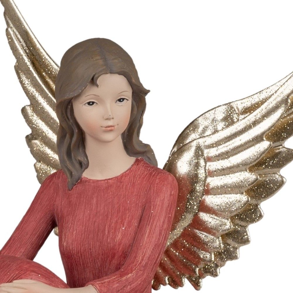 Eine Figur eines Engels mit goldenen Flügeln und braunen Haaren, gekleidet in ein rotes Oberteil. De