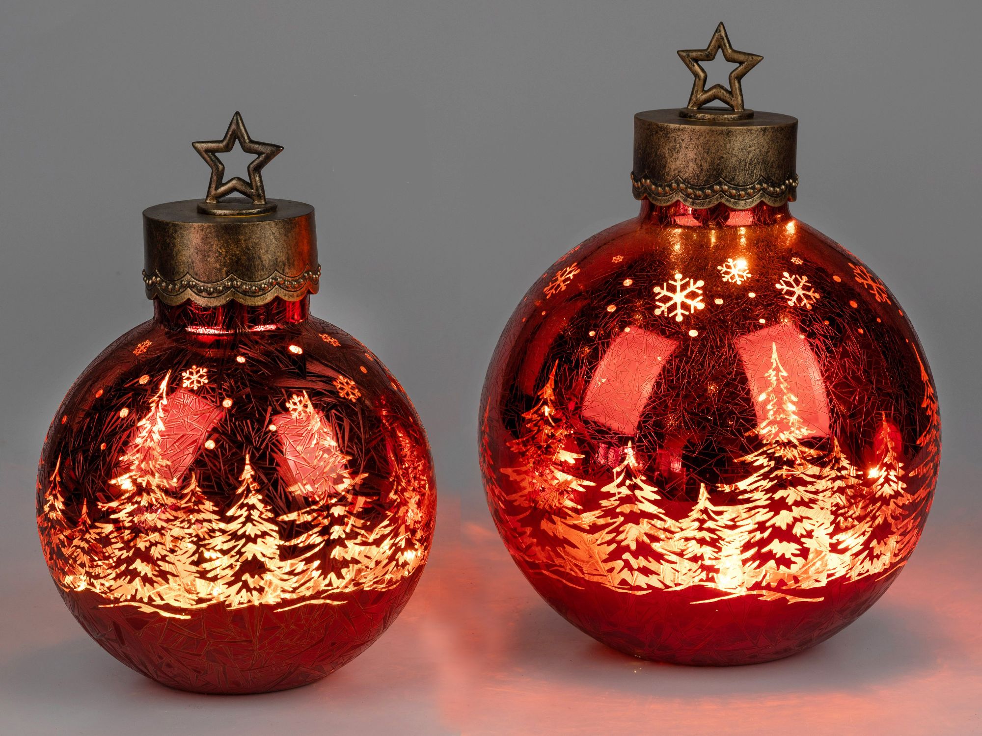 Zwei große, rote Weihnachtskugeln mit Sternenaufsatz und eingravierten Tannenbäumen und Schneeflocke