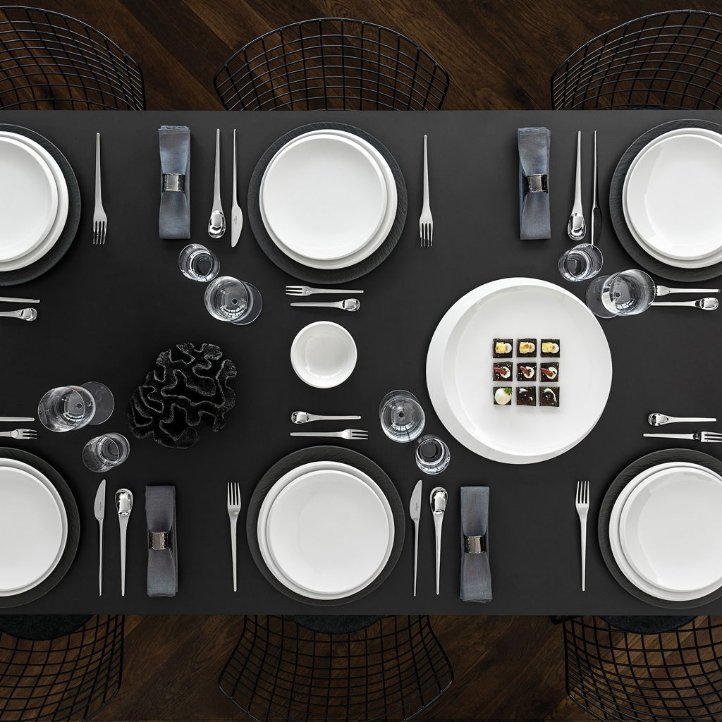 Ein gedeckter Tisch mit Tellern, Besteck und Gläsern auf schwarzem Tisch
