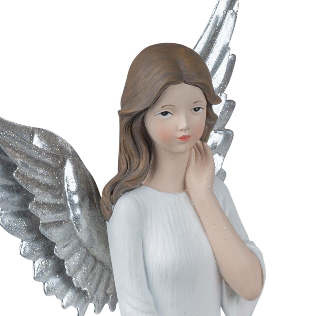 Eine Figur eines Engels mit langen, silbernen Flügeln und braunen Haaren, die in einem weißen Gewand