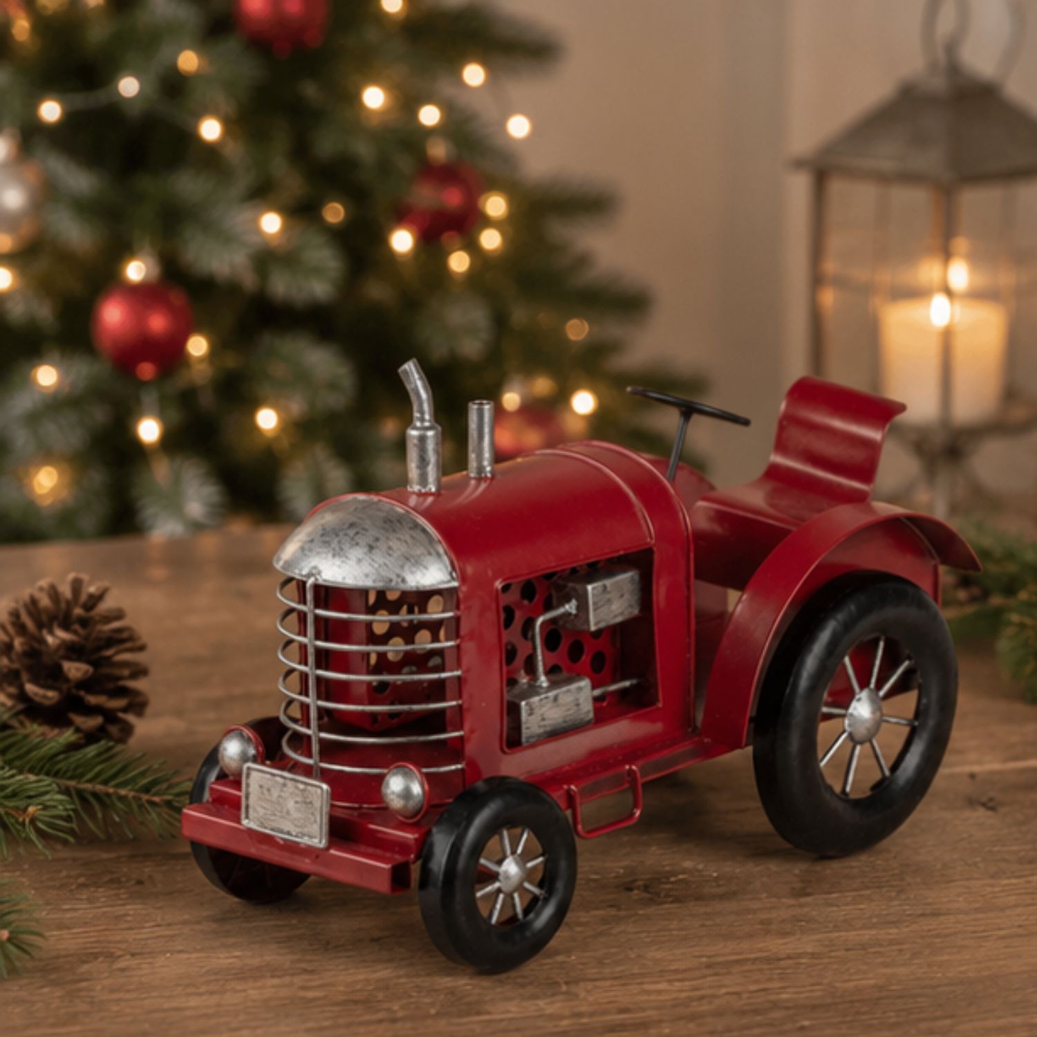 Rotes Spielzeugtraktor-Modell auf Holztisch, hinten unscharfer Weihnachtsbaum mit Lichtern