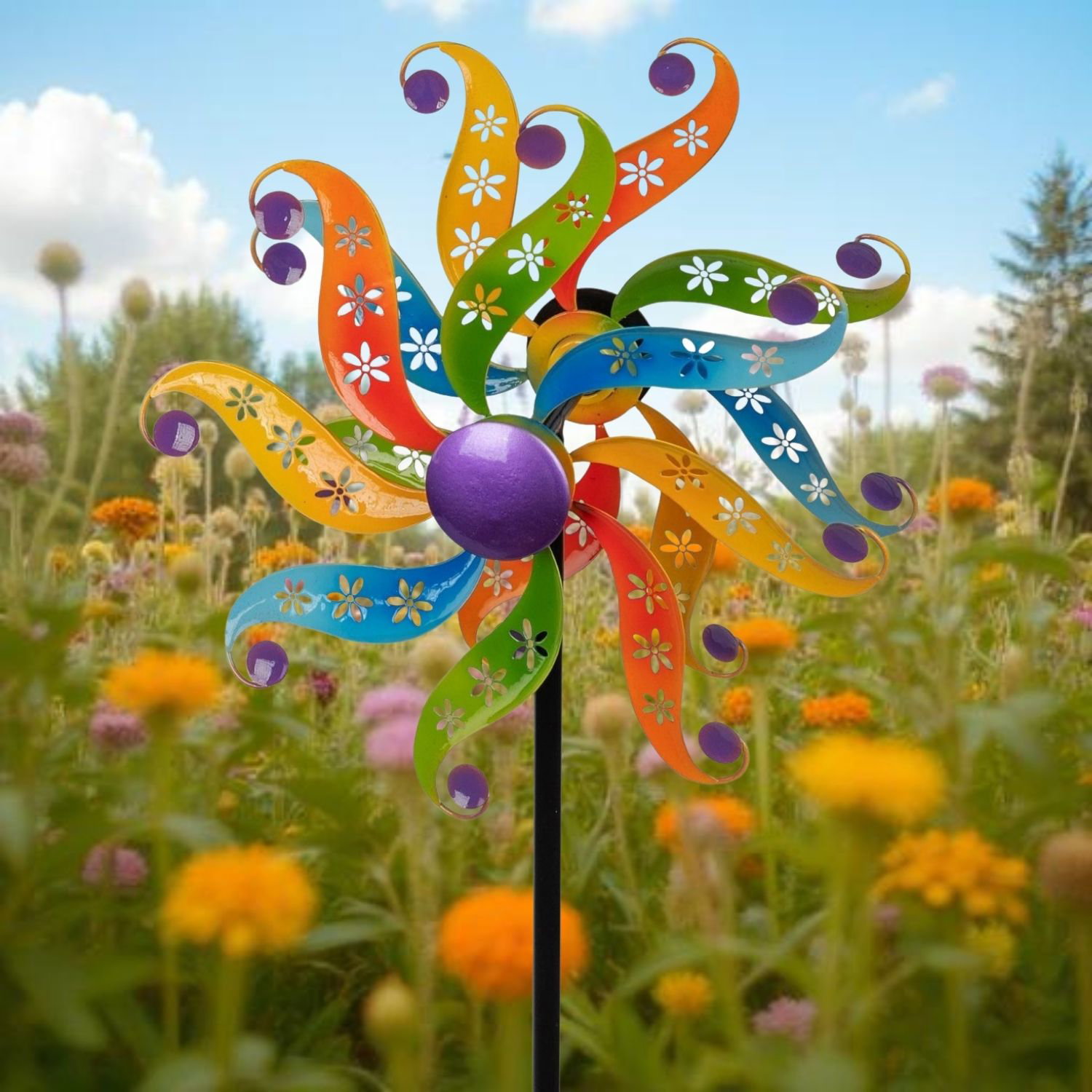 Bunte Windmühle in einem blühenden Garten mit vielen Blumen im Hintergrund