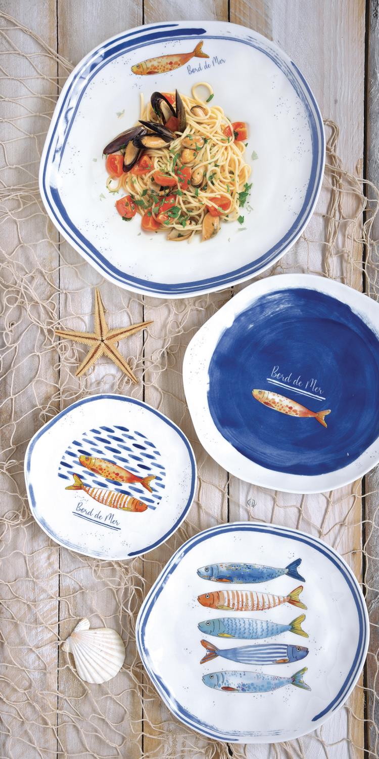 Ein Tisch mit verschiedenen Tellern: ein großer Teller mit Pasta und Muscheln, drei kleinere Teller mit Fischmotiven. Dekoratives Netz und Muschel.