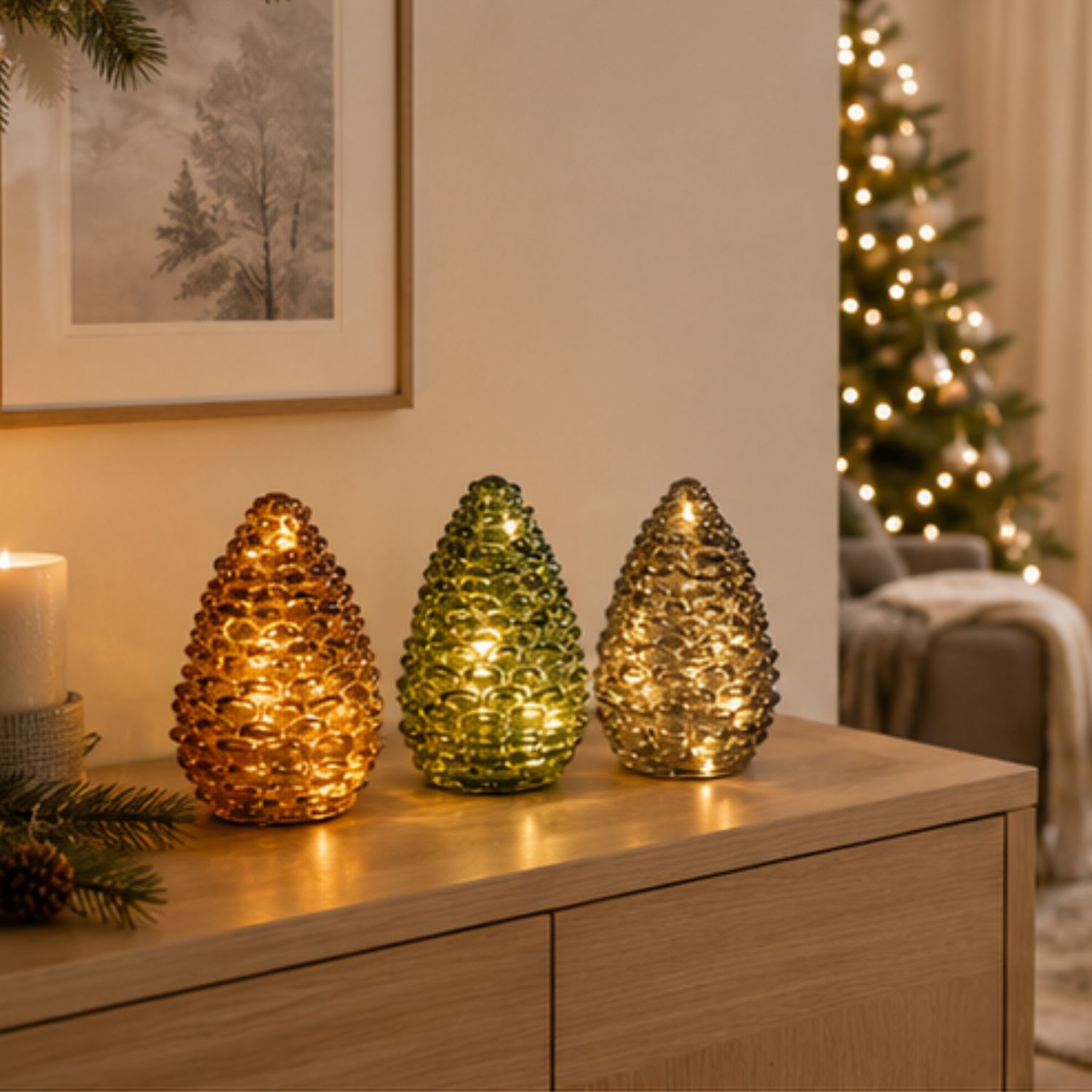 Drei leuchtende Glaszapfen in Gold, Grün und Silber auf einer Holzkommode, Lichterbaum im Hintergr