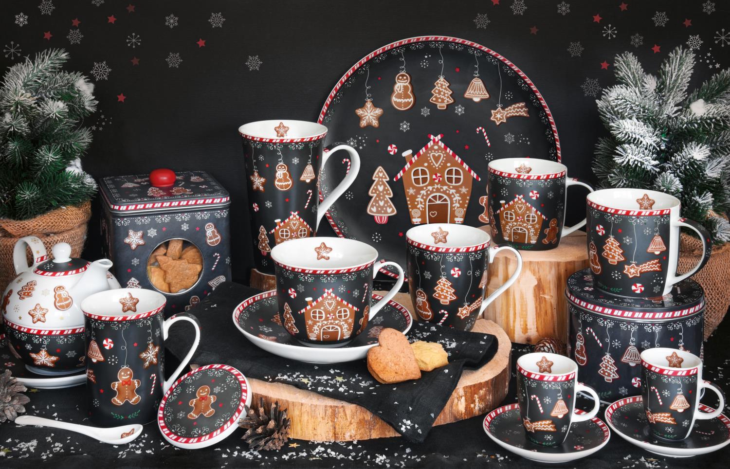 Dekoratives Geschirrset mit weihnachtlichen Motiven, Plätzchen und Tannenzweigen auf einem rustikalen Untergrund.