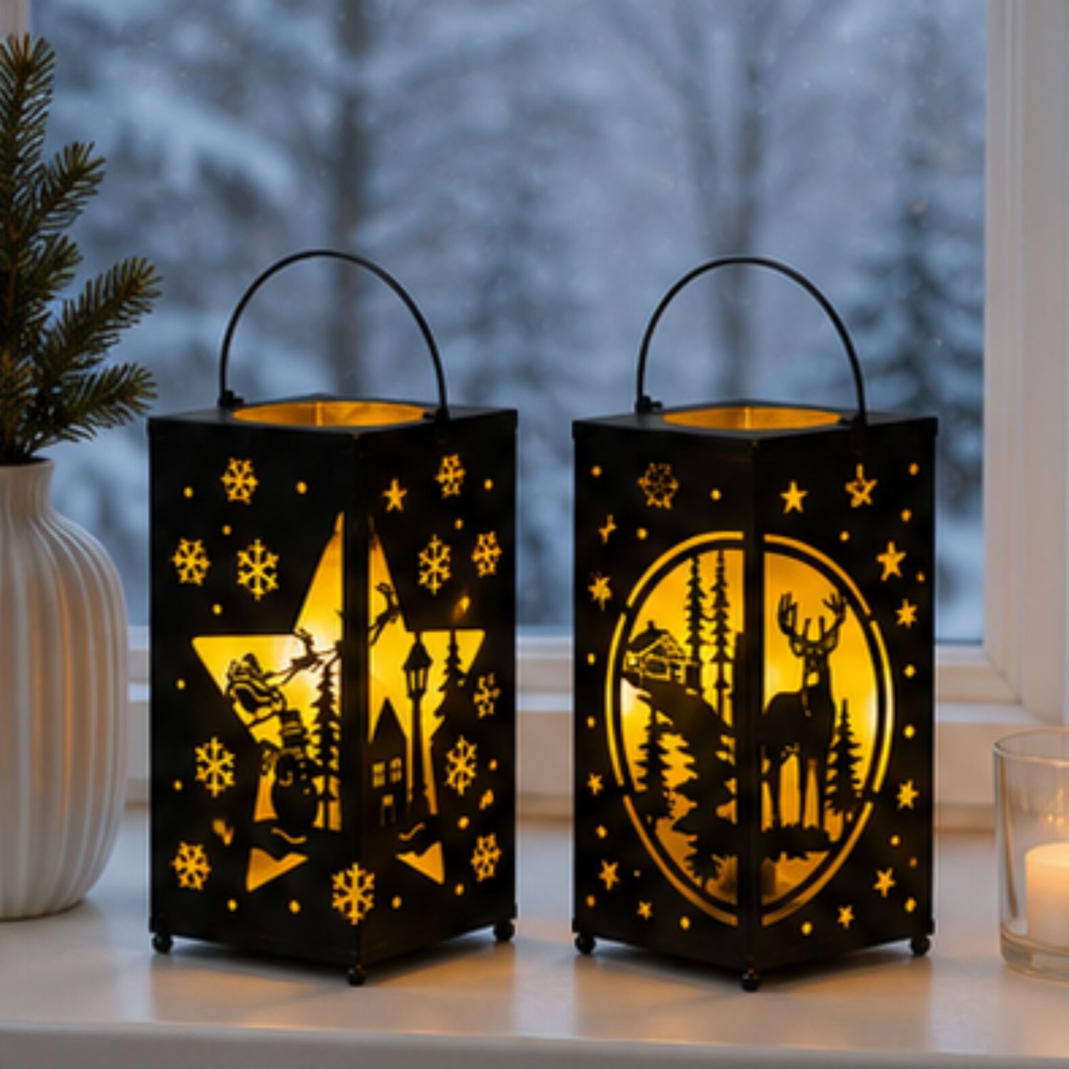 Zwei leuchtende Laternen mit Wintermotiven auf einer Fensterbank, Kerze und Tannenzweig daneben