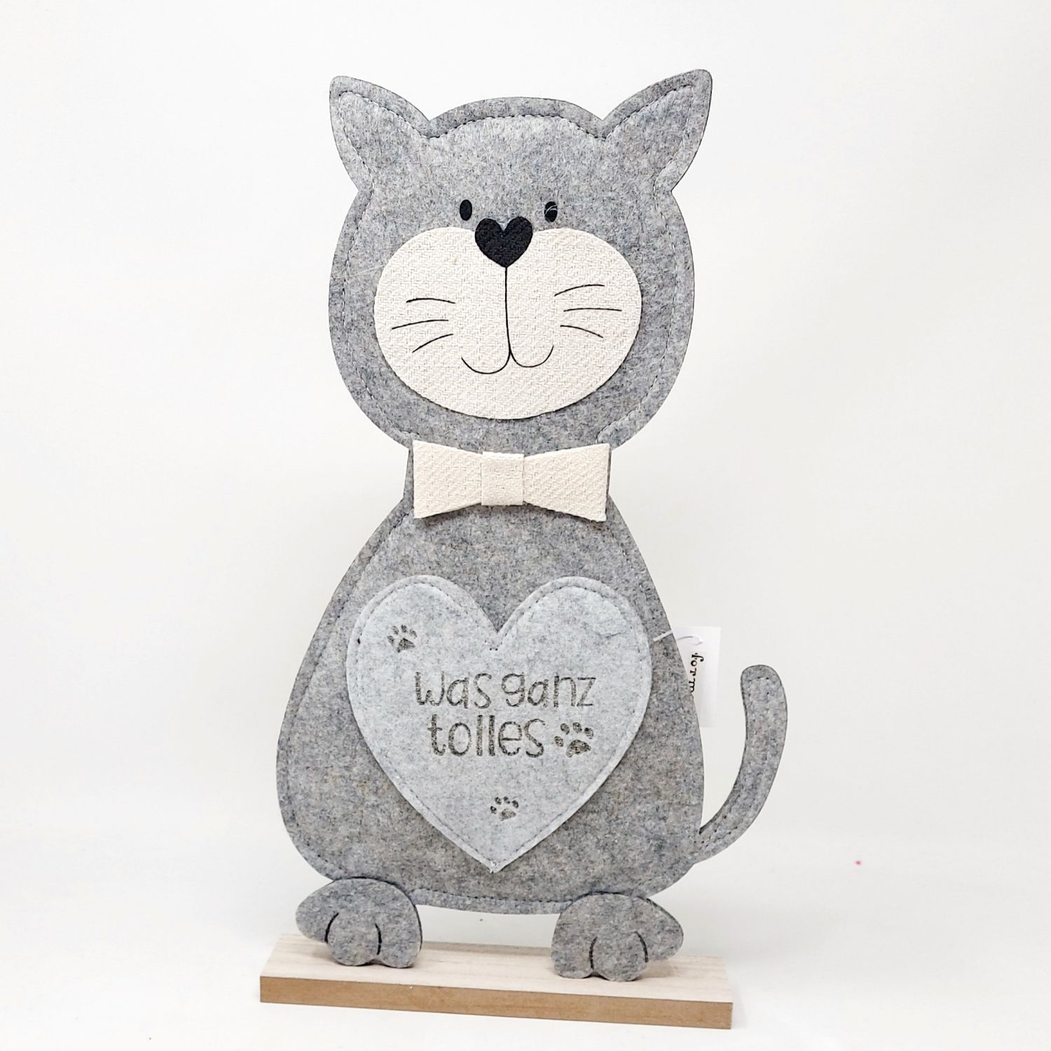 Graue Katzenfigur aus Filz mit einem Herz und Pfotenabdrücken, trägt eine Schleife. Steht auf einem