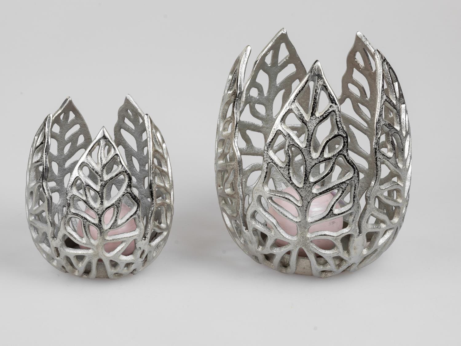 Zwei dekorative Teelichthalter aus silberfarbenem Metall mit Blattmuster, einer größer als der andere, auf hellem Hintergrund.