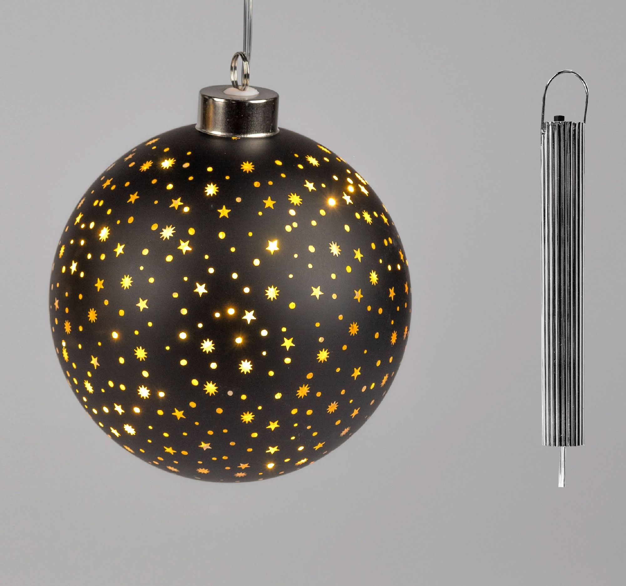 Schwarze Weihnachtskugel mit goldenen Sternenmustern, hängend an einem silbernen Aufhänger. Rechts e