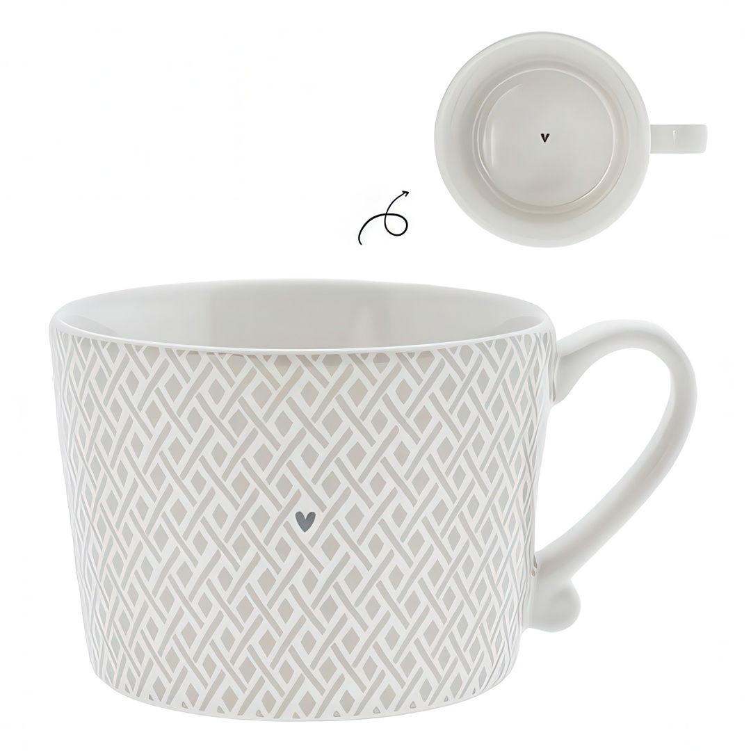 Weiße Tasse mit geometrischem Muster und Herzmotiv, seitlich mit Henkel, von oben sichtbar. Unterseite zeigt ein kleines "v".