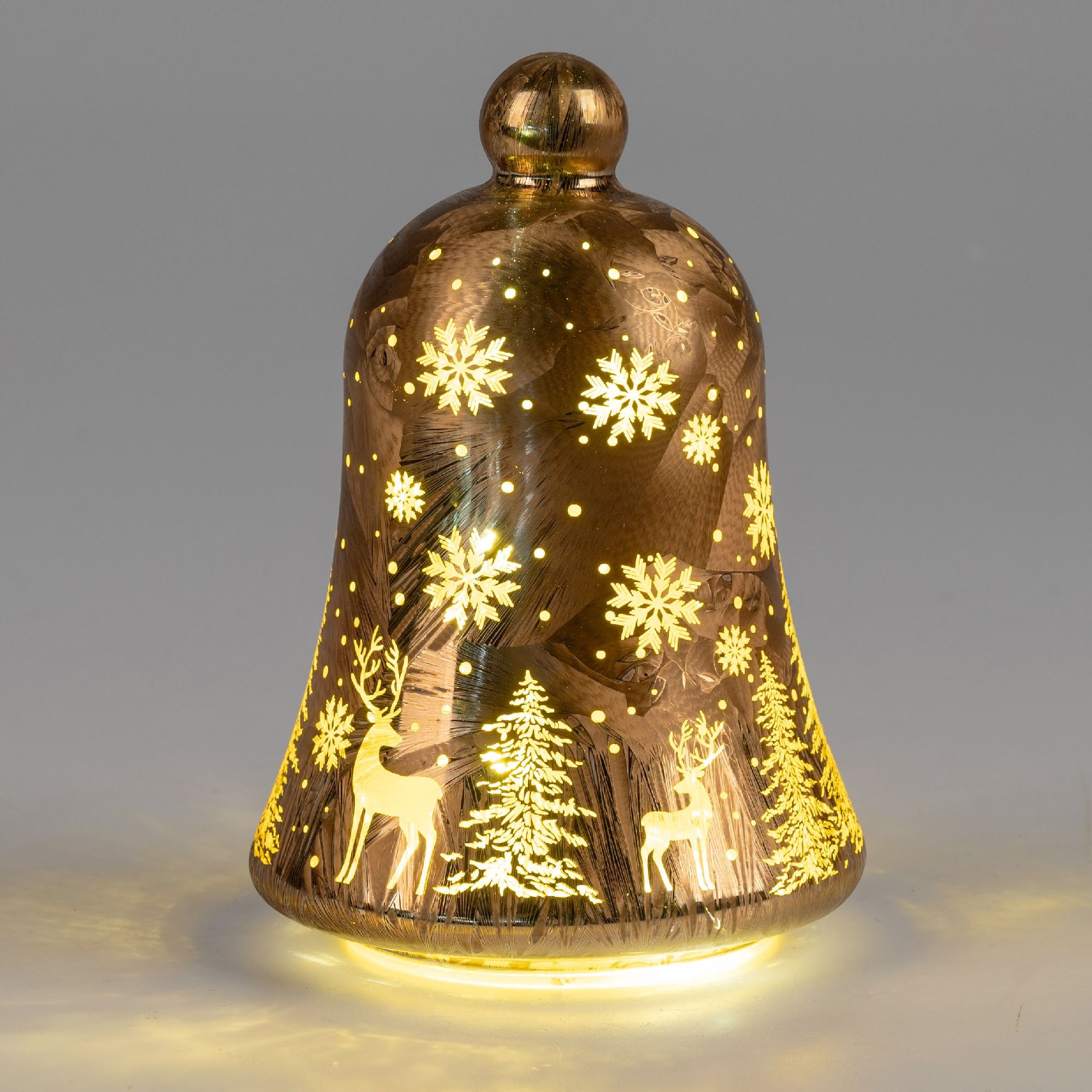 Eine gläserne Glocke mit goldenen Schneeflocken und Weihnachtsmotiven, beleuchtet von unten.