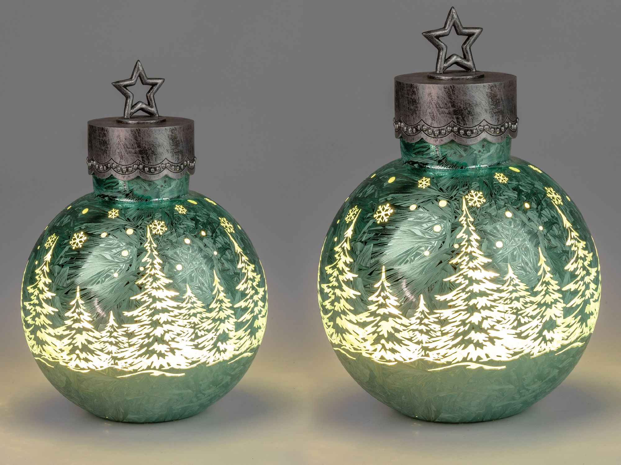 Zwei leuchtende Weihnachtskugeln in Grün mit einem Stern oben und einem Muster aus Tannenbäumen und