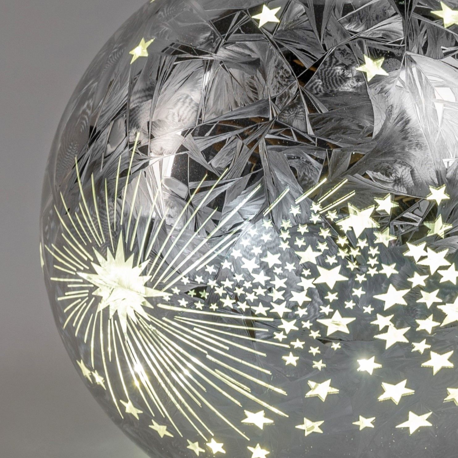 Kugel mit glitzerndem, sternenförmigem Muster und strahlenden Linien auf einer transparenten Oberflä