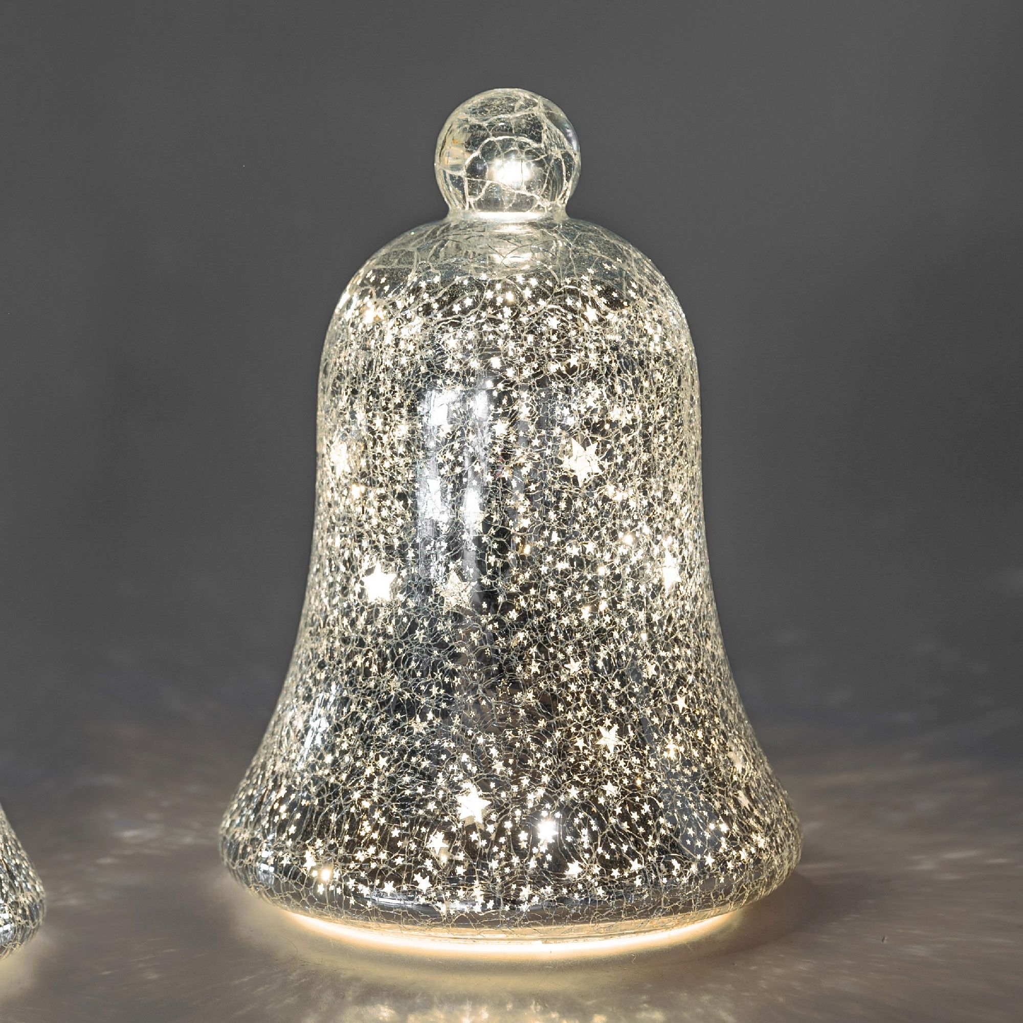 Glasglocke mit glitzernder Oberfläche und kleinen, leuchtenden Sternen. Hintergrund in grauer Farbe.