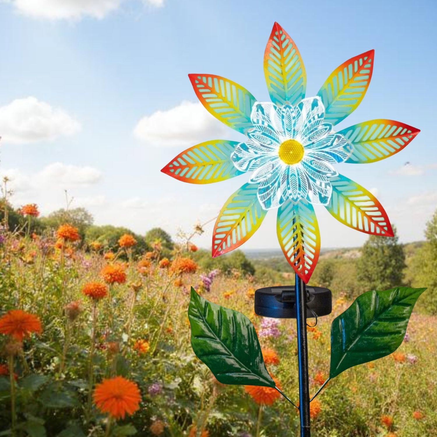 Bunte Windmühle in Blütenform auf Wiese mit orangefarbenen Blumen unter blauem Himmel